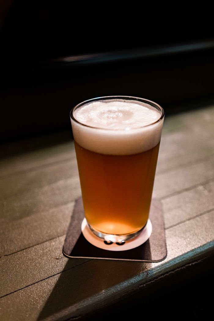 gallery-2 A frothy beer in a clear glass resting on a coaster on a wooden table. Perfect for beverage themes.