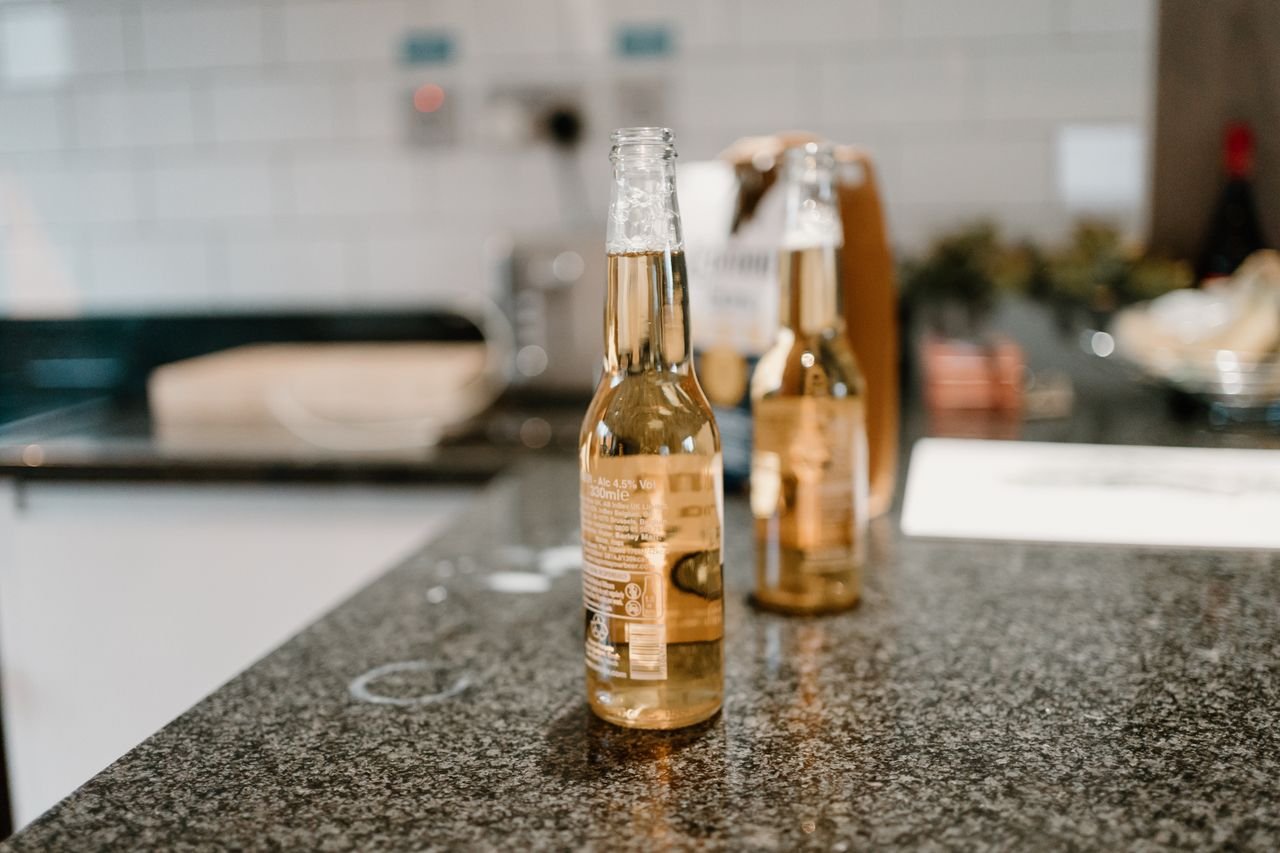 gallery-4 Two bottles of beer on a sleek granite counter with a blurred kitchen background.