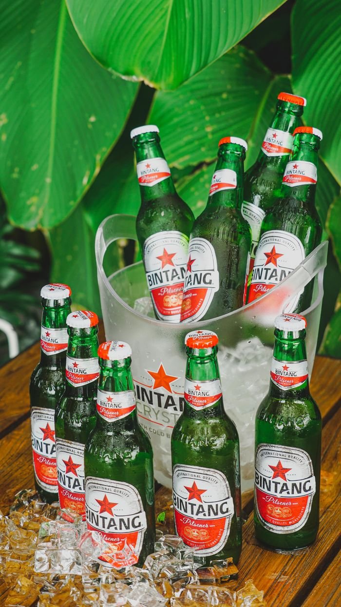 gallery-3 Chilled Bintang beer bottles in ice against lush greenery, perfect for tropical refreshment.